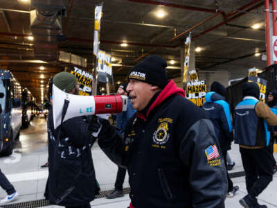 An Amazon teamster chants into a megaphone as other striking workers march around him