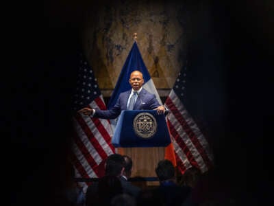 Eric Adams speaks behind a podium and in front of U.S. and New York State flags