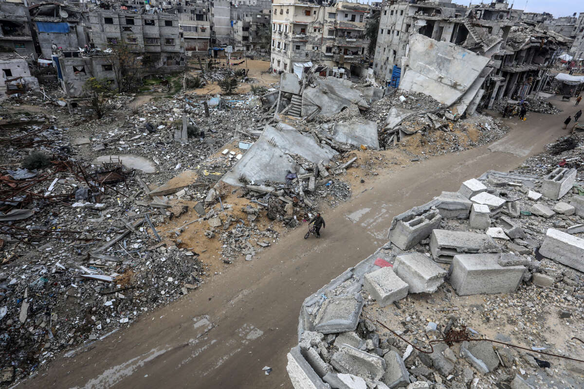 a man walks his bike through a leveled Palestinian neighborhood