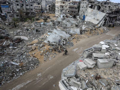 a man walks his bike through a leveled Palestinian neighborhood