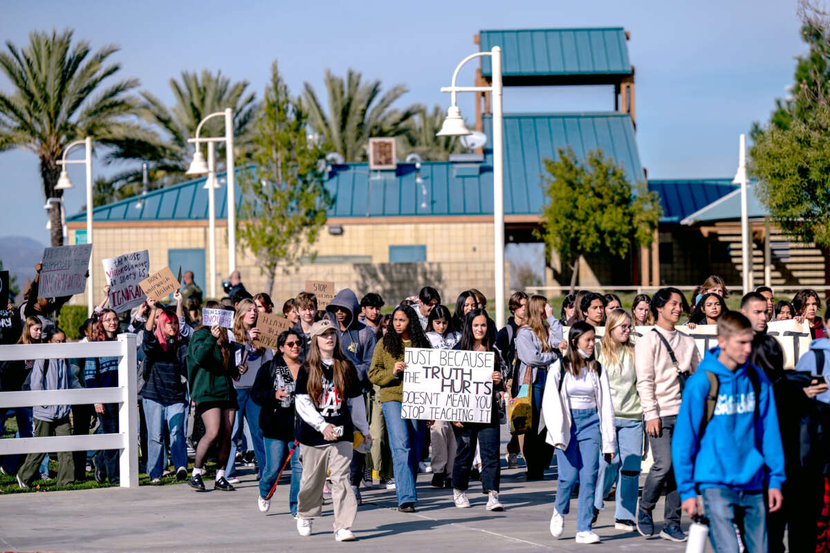 Students stage a walk-out from school while marching behind a banner that reads "JUST BECAUSE THE TRUTH HURTS DOESN'T MEAN STOP TEACHING IT"