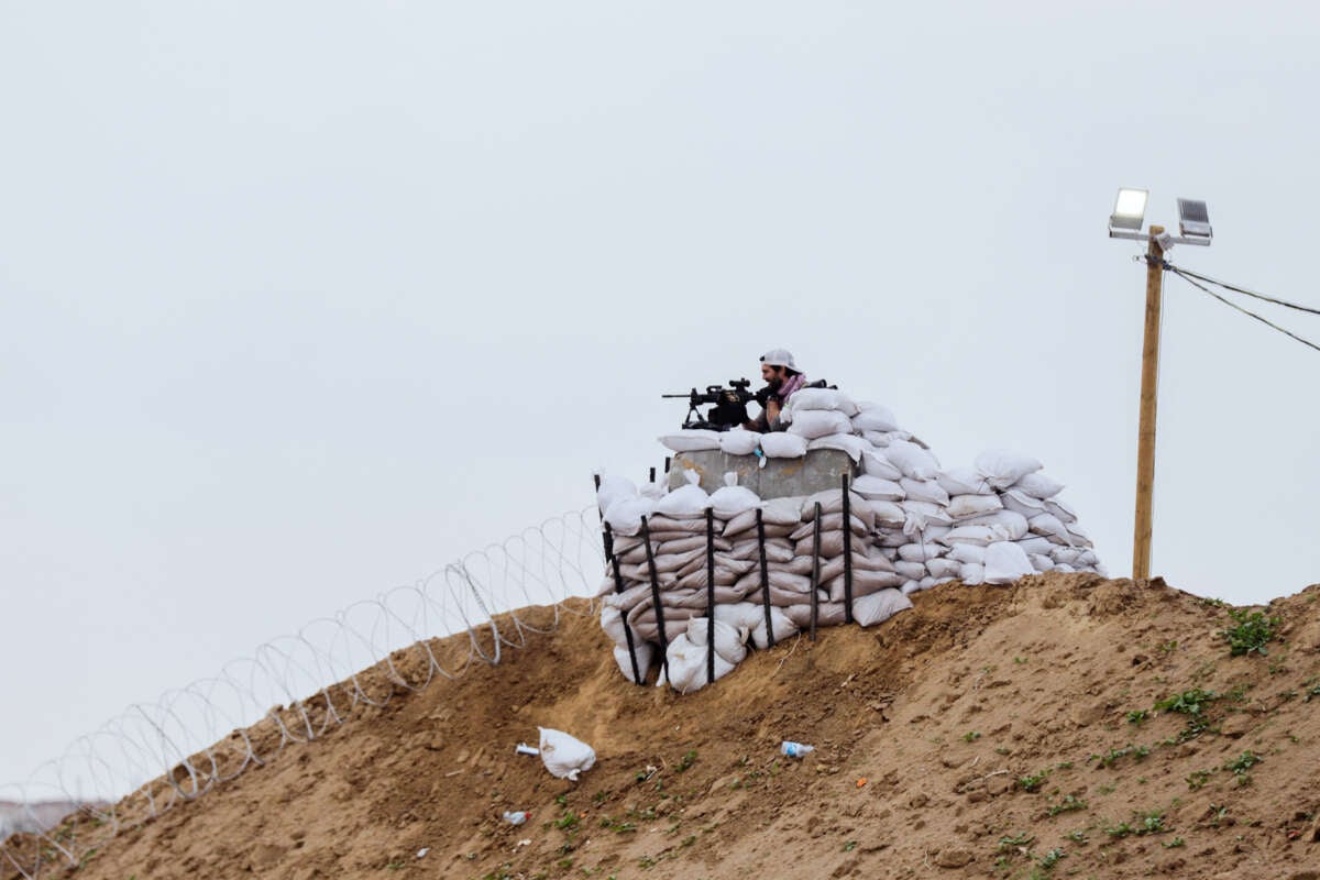 A member of the Egyptian-Qatari security forces watches from an observation post as displaced Palestinians cross the Netzarim Corridor toward the north, following the withdrawal of Israeli troops in central Gaza, on February 10, 2025.