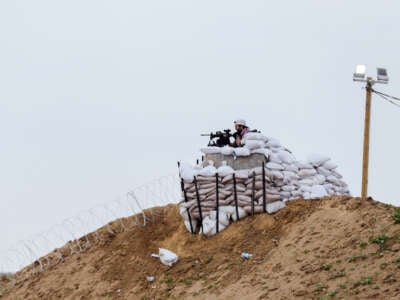 A member of the Egyptian-Qatari security forces watches from an observation post as displaced Palestinians cross the Netzarim Corridor toward the north, following the withdrawal of Israeli troops in central Gaza, on February 10, 2025.