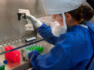 A Centers for Disease Control (CDC) scientist uses a pipette to transfer H7N9 virus into vials for sharing with partner laboratories for public health research purposes.