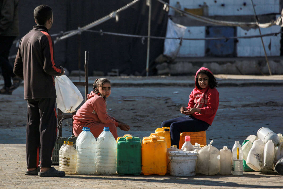 Children displaced by conflict sheltering at a school wait to fill up their water containers from a cistern in Khan Yunis in the southern Gaza Strip on January 13, 2025.