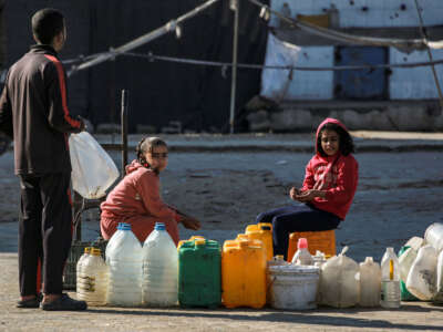 Children displaced by conflict sheltering at a school wait to fill up their water containers from a cistern in Khan Yunis in the southern Gaza Strip on January 13, 2025.