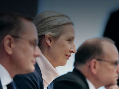 Three German people sit next to eachother at a table