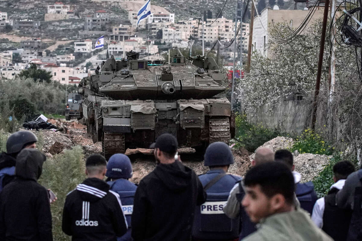 People look on as Israeli tanks enter the Jenin camp for Palestinian refugees in the occupied West Bank, on February 23, 2025.