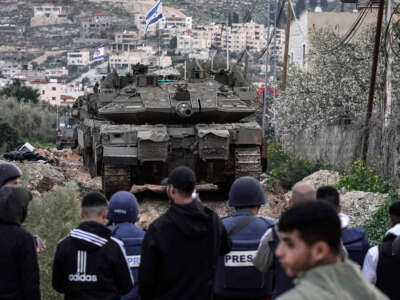 People look on as Israeli tanks enter the Jenin camp for Palestinian refugees in the occupied West Bank, on February 23, 2025.