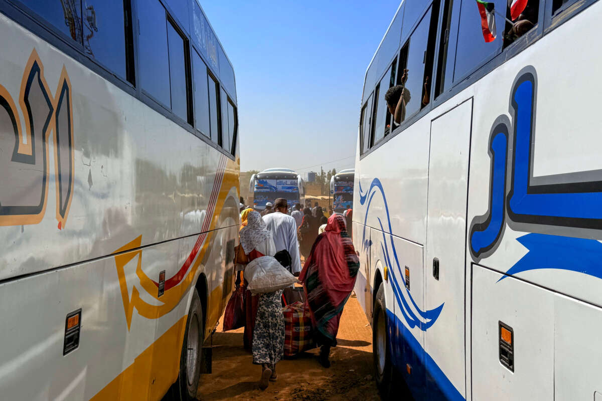 People displaced by the ongoing war in Sudan disembark buses as they return to Wad Madani in the Jazira state after the city was retaken by the Sudanese army from the Rapid Support Forces, on February 6, 2025.