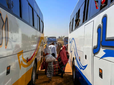 People displaced by the ongoing war in Sudan disembark buses as they return to Wad Madani in the Jazira state after the city was retaken by the Sudanese army from the Rapid Support Forces, on February 6, 2025.