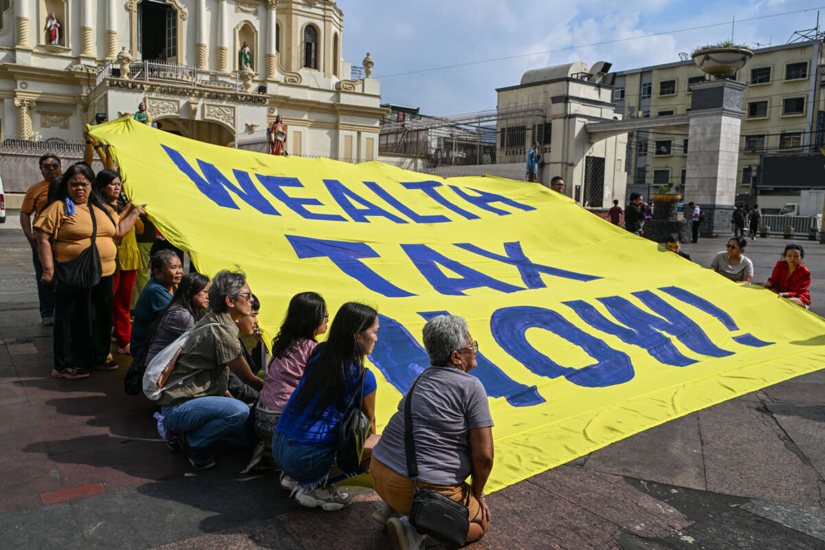 Members of an environmental group hold a banner reading Wealth Tax Now during a demonstration to highlight the issues of poverty and inequality in the region in Manila on January 20, 2025, which coincides with the opening day of the World Economic Forum in Davos.