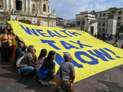 Members of an environmental group hold a banner reading Wealth Tax Now during a demonstration to highlight the issues of poverty and inequality in the region in Manila on January 20, 2025, which coincides with the opening day of the World Economic Forum in Davos.