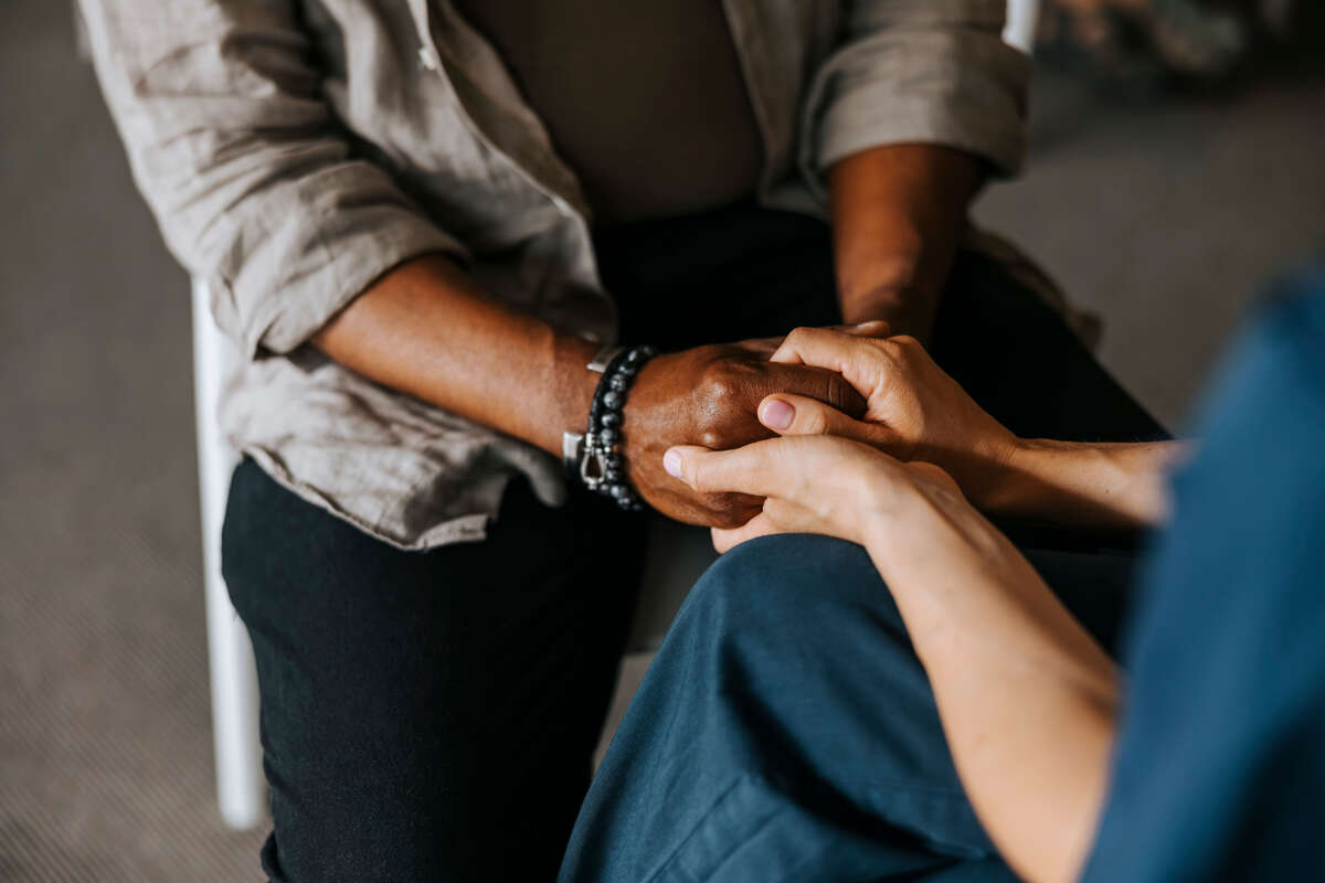 Person holds hands with counselor during therapy