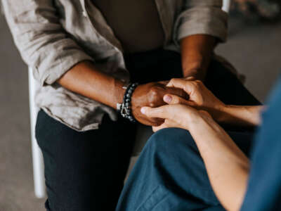 Person holds hands with counselor during therapy