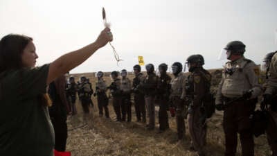 A phalanx of National Guard and police advance toward a water protector holding an eagle feather at a camp near the Standing Rock Reservation in the direct path of the Dakota Access pipeline (DAPL) where 117 people were arrested, on October 27, 2016.