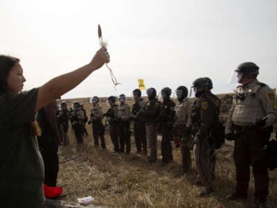 A phalanx of National Guard and police advance toward a water protector holding an eagle feather at a camp near the Standing Rock Reservation in the direct path of the Dakota Access pipeline (DAPL) where 117 people were arrested, on October 27, 2016.