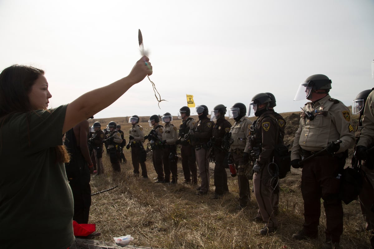 A phalanx of National Guard and police advance toward a water protector holding an eagle feather at a camp near the Standing Rock Reservation in the direct path of the Dakota Access pipeline (DAPL) where 117 people were arrested, on October 27, 2016.