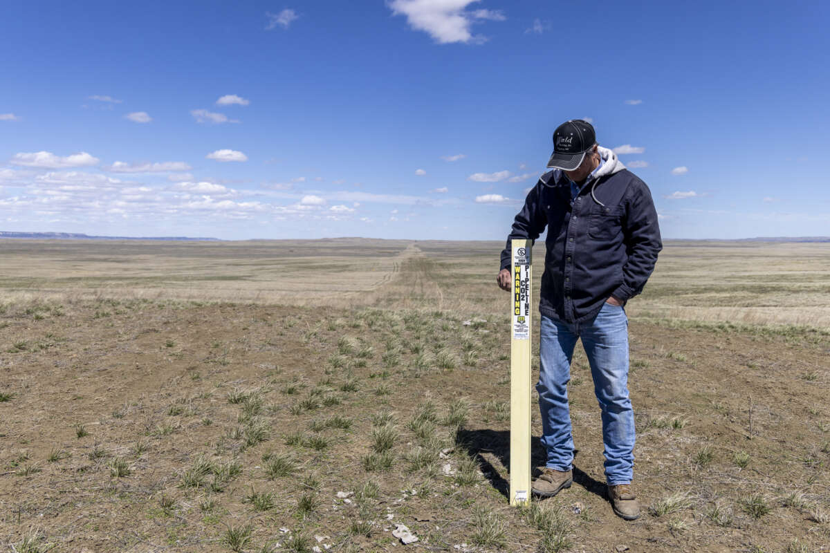 Carter County rancher Mike Hansen stands next to Denbury's carbon pipeline on April 22, 2021, on his Bureau of Land Management (BLM) allotment in Hammond, Montana, part of the 110,000 acres of BLM land where the Snowy River carbon sequestration project has been proposed. Hansen is concerned about the impacts of the project and safety hazards associated with it.