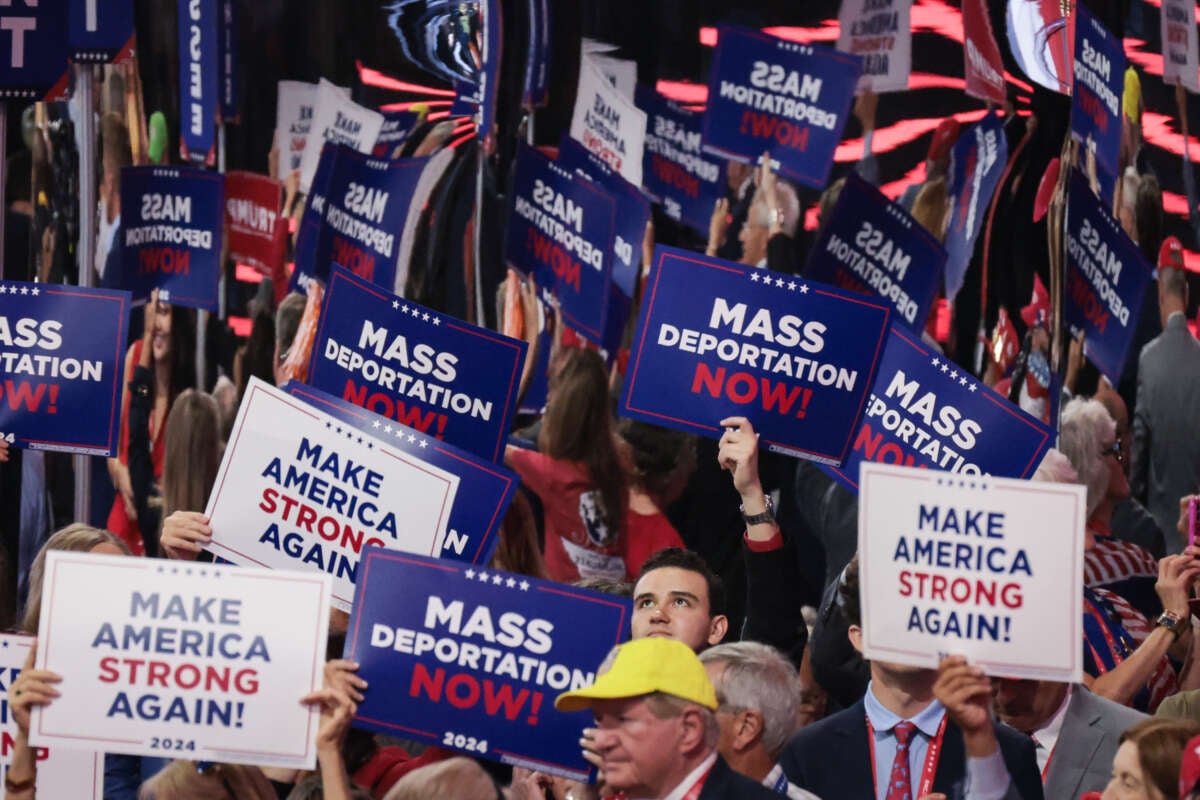 People hold signs that read "Mass Deportation Now" and "Make America Strong Again" on the third day of the Republican National Convention at the Fiserv Forum on July 17, 2024 in Milwaukee, Wisconsin.