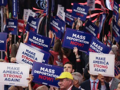 People hold signs that read "Mass Deportation Now" and "Make America Strong Again" on the third day of the Republican National Convention at the Fiserv Forum on July 17, 2024 in Milwaukee, Wisconsin.