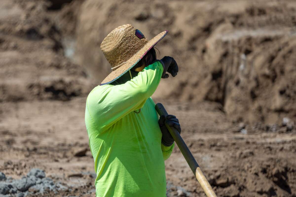 A construction worker takes a quick break to wipe his brow while digging a trench with a shovel amid a heat wave in Irvine, California, on September 5, 2024.