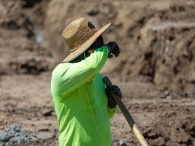 A construction worker takes a quick break to wipe his brow while digging a trench with a shovel amid a heat wave in Irvine, California, on September 5, 2024.