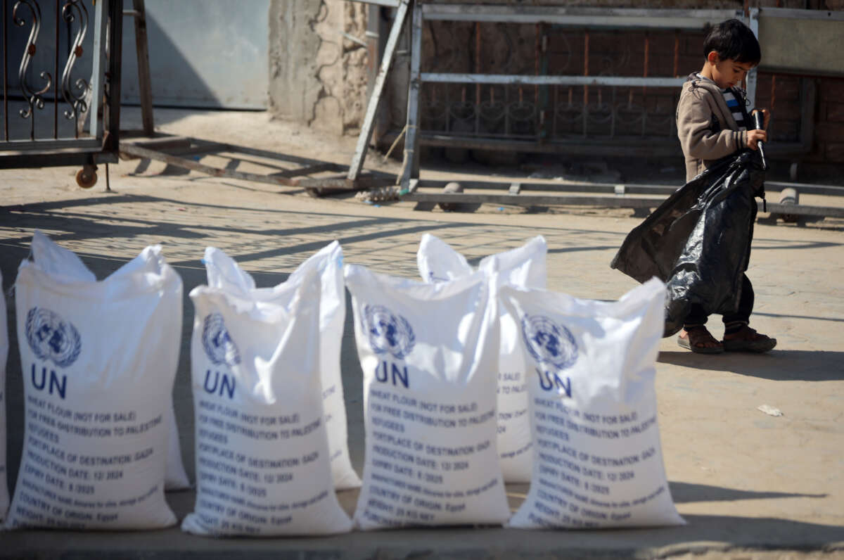 A Palestinian boy stands next to sacks of flour at the distribution center of the United Nations Relief and Works Agency for Palestine Refugees (UNRWA) in Deir al-Balah, central Gaza Strip, on January 29, 2025.