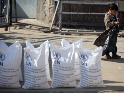 A Palestinian boy stands next to sacks of flour at the distribution center of the United Nations Relief and Works Agency for Palestine Refugees (UNRWA) in Deir al-Balah, central Gaza Strip, on January 29, 2025.