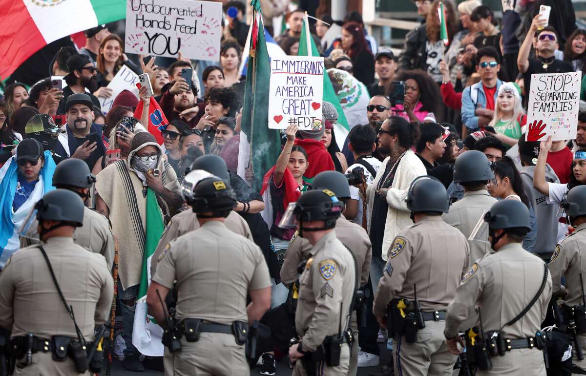 Anti-deportation demonstrators protest the Trump administration's deportations near police officers blocking an entrance to the 101 freeway on February 2, 2025, in Los Angeles, California.