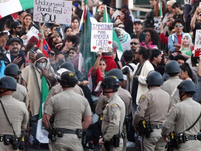 Anti-deportation demonstrators protest the Trump administration's deportations near police officers blocking an entrance to the 101 freeway on February 2, 2025, in Los Angeles, California.