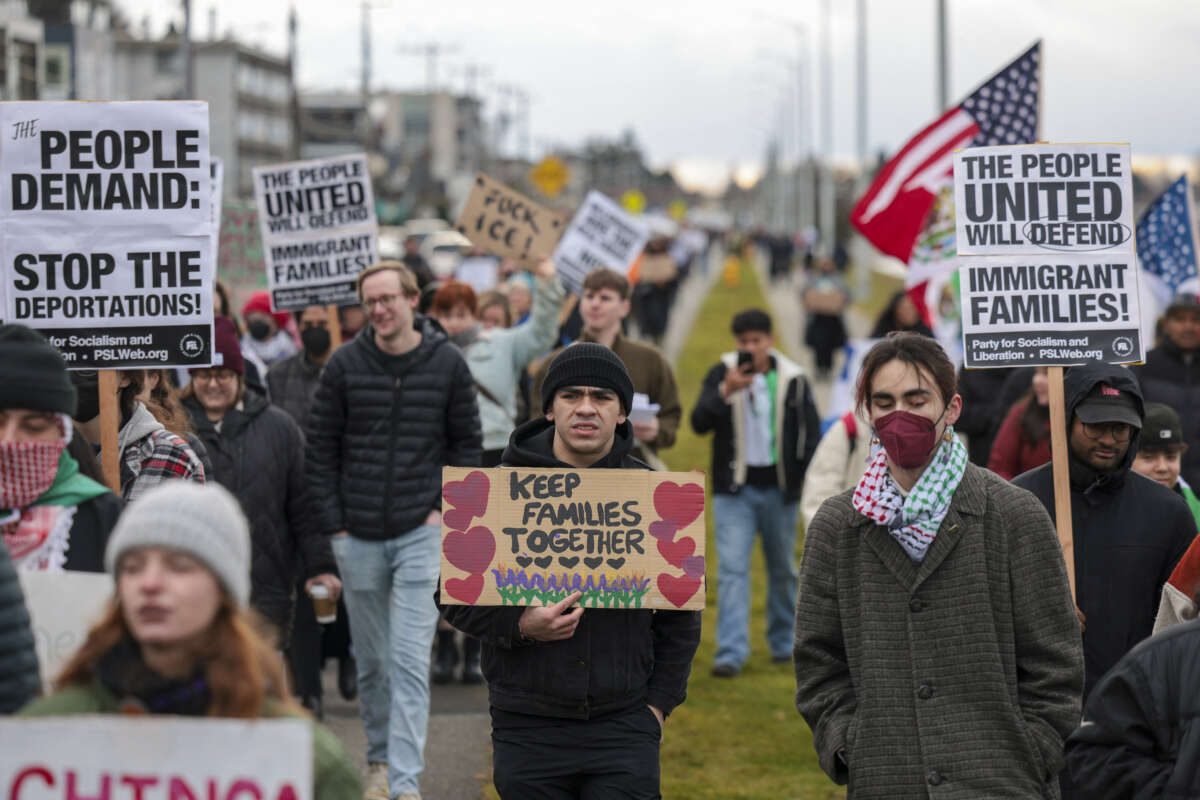 Protesters hold signs during a march against Immigration and Customs Enforcement (ICE) entitled "Get our Gente Out of Guantanamo Bay!" in Seattle, Washington, on February 8, 2025.