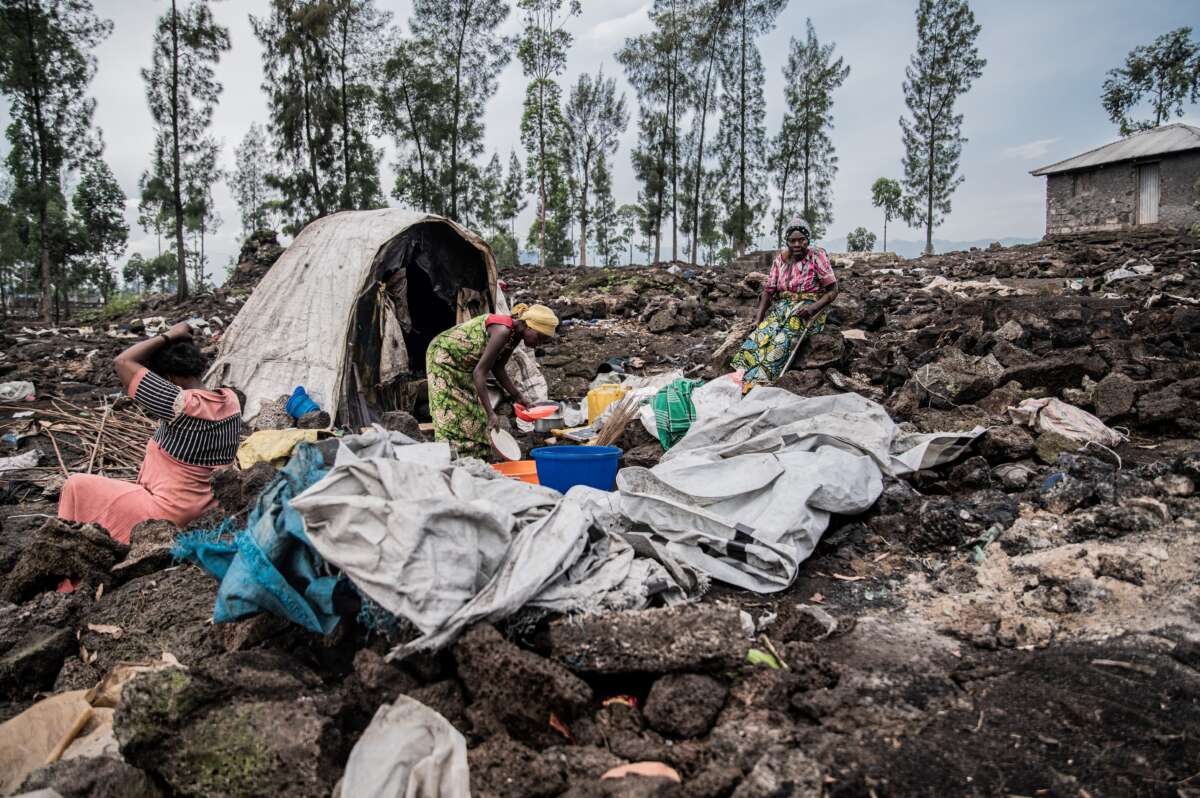 An elderly woman and her two daughters-in-law stand in front of one of the last remaining shelters in the Bulengo internally displaced persons camp after it was burned down, in Bulengo, Democratic Republic of Congo, on February 17, 2025.