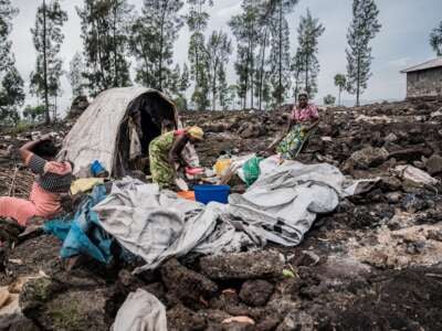 An elderly woman and her two daughters-in-law stand in front of one of the last remaining shelters in the Bulengo internally displaced persons camp after it was burned down, in Bulengo, Democratic Republic of Congo, on February 17, 2025.