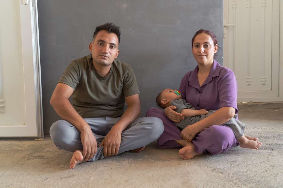 Fadil Murat Shamo sits with his wife and small child that lays in her arms.