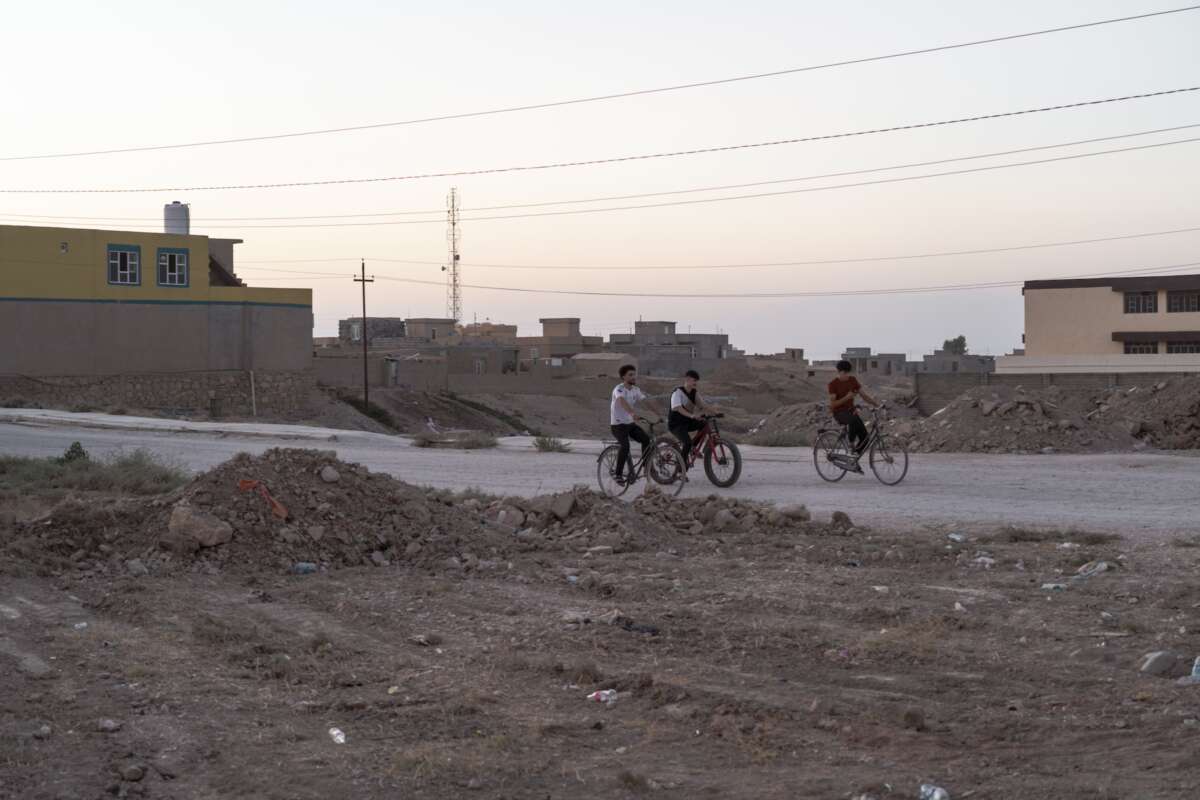 Young people ride bikes through a village in northern Sinjar, where Yazidi have recently begun to return.