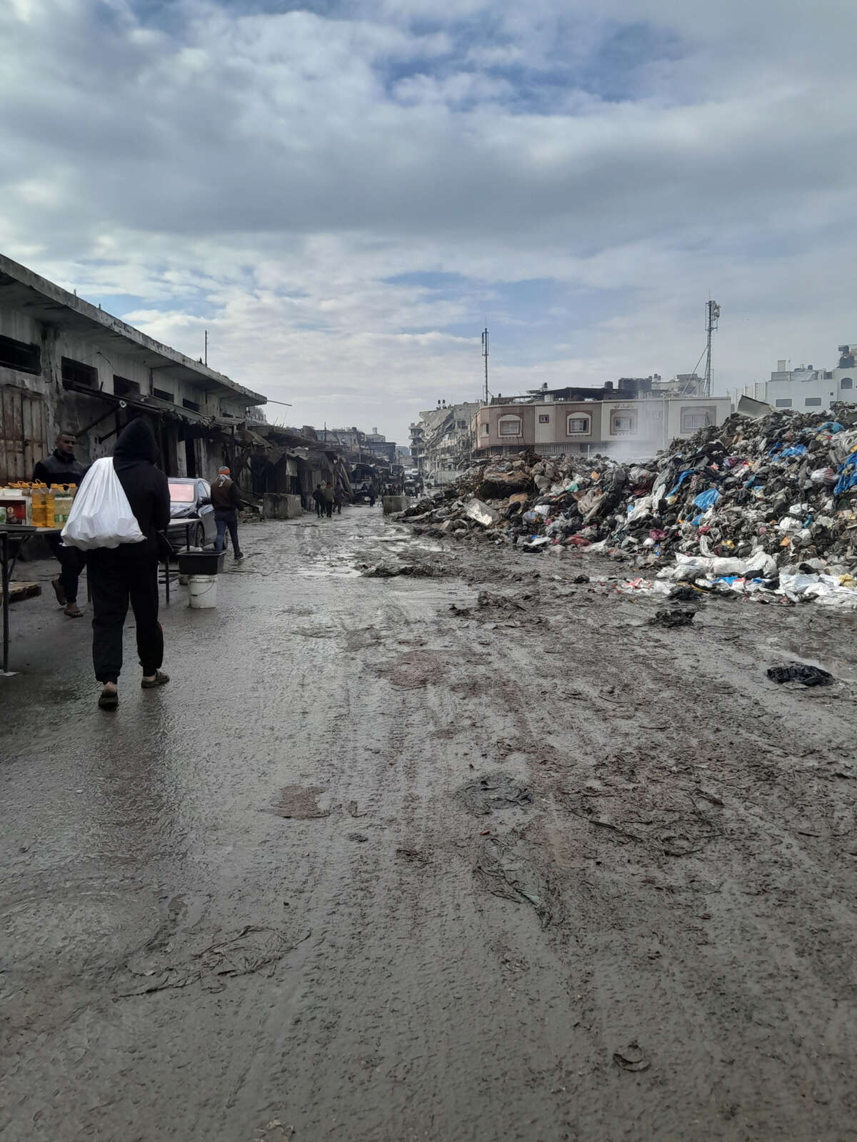 A man walks past a pile of garbage that is taller than the average human man