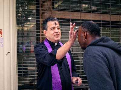 A priest with an ashen cross on his forehead anoints a man's brow