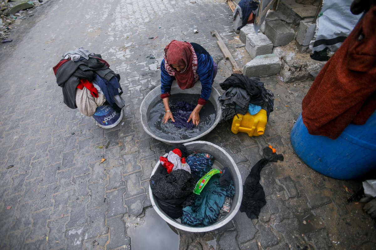 A woman washes laundry in a basin outdoors