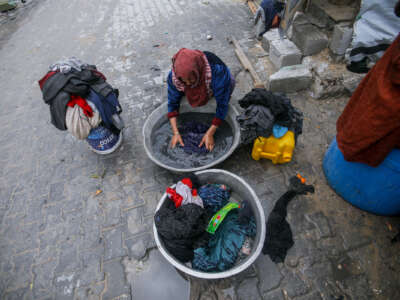 A woman washes laundry in a basin outdoors