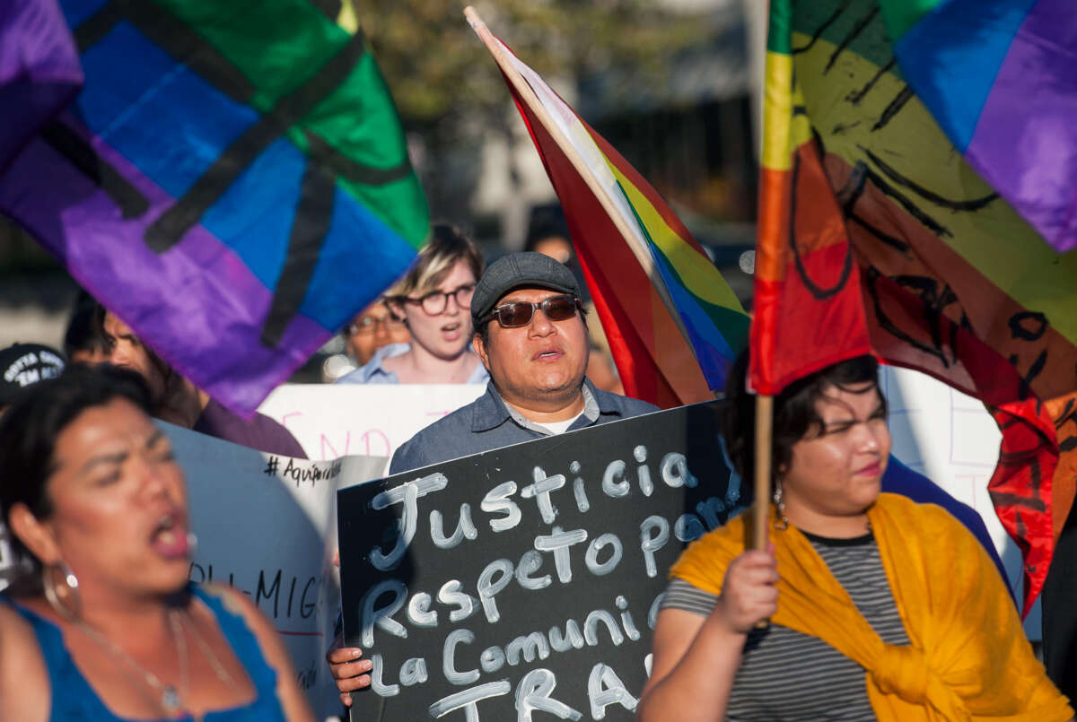 People holding rainbow flags protest outdoors