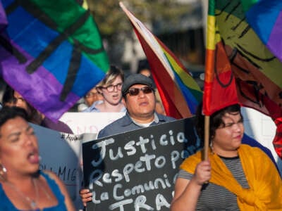 People holding rainbow flags protest outdoors