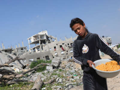 A Palestinian girl carries a food ration back to her family in Jabalia in the northern Gaza Strip on February 17, 2025.