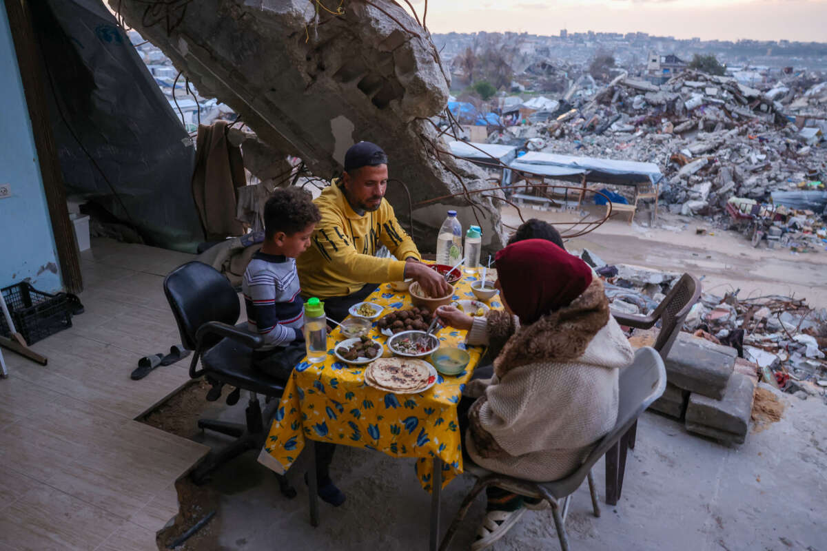 Tamer Hassan al-Shafai eats an iftar meal, the breaking of the fast, with his family in their destroyed house amid the rubble of buildings in Beit Lahia in the northern Gaza Strip on March 4, 2025, during the Muslim holy fasting month of Ramadan.