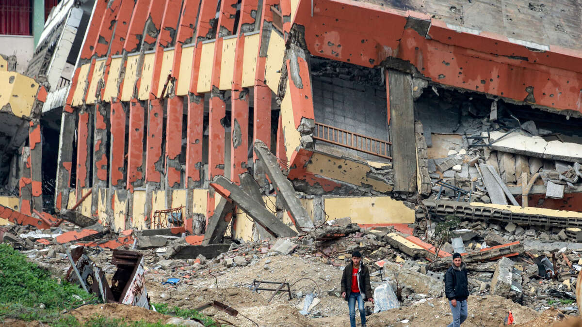 Youths walk past a destroyed secondary school in the north of Gaza City, on February 10, 2025.