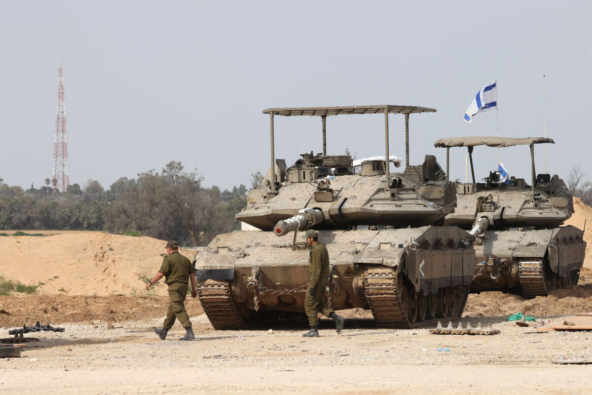 Israeli army soldiers walk past tanks at a position near Israel's southern border with the Gaza Strip on March 6, 2025.