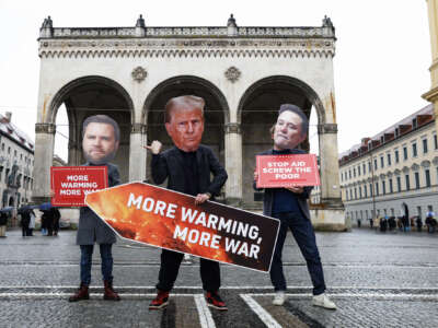 Three protesters dressed up as JD Vance, Donald Trump (holding a sign reading "MORE WARMING, MORE WAR" and Elon Musk pose for a photo