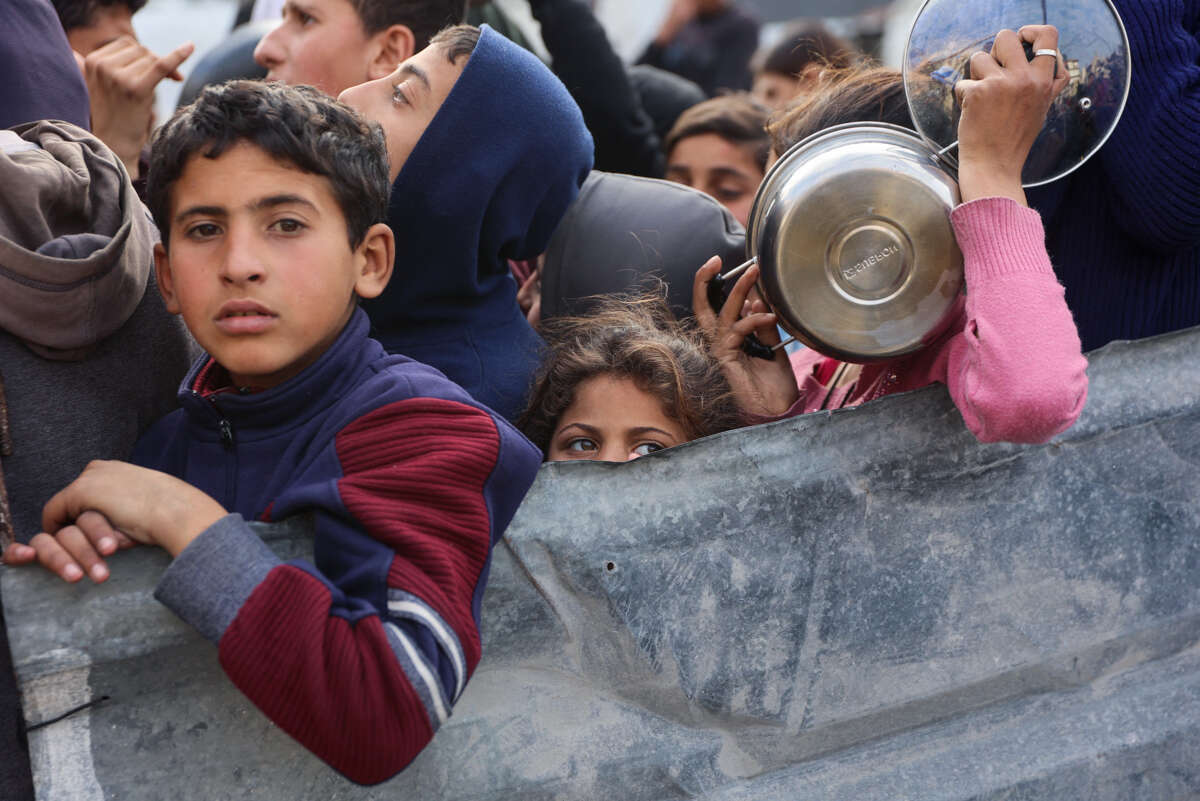 Palestinian children wait to receive food from an aid station