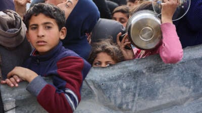 Palestinian children wait to receive food from an aid station