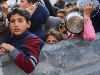 Palestinian children wait to receive food from an aid station